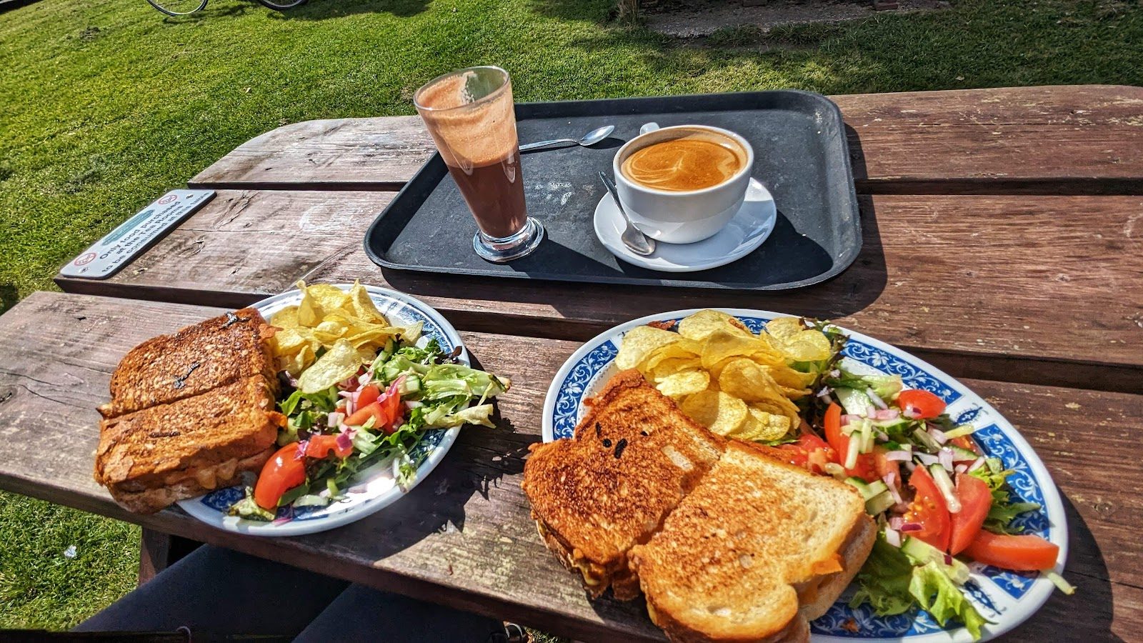 Toasted sandwiches with salad and crisps on an outdoor table